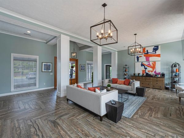 Modern living room with light blue walls, gray sofas, orange accents, and abstract wall art.