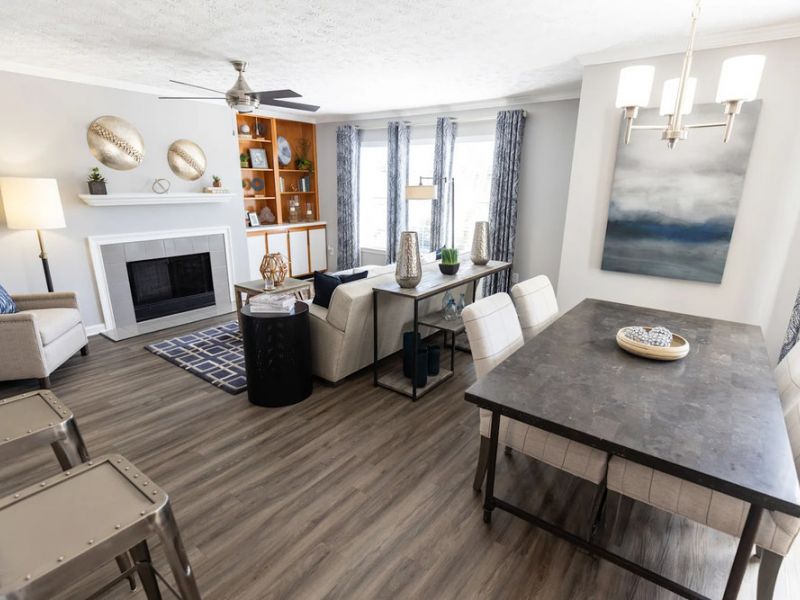 Modern living and dining room with gray floors, neutral furniture, and large windows letting in natural light.